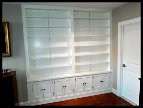 Custom white bookcase designed to match existing cabinetry; 8 cabinet door base with open-face shelving above.