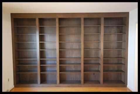 Walnut floor-to-ceiling wall-to-wall built-in bookcases, 5-tier library with 3-inch wide vertical dividers.