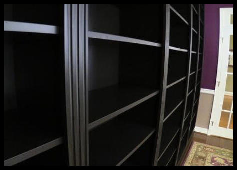 Modern black-on-black built-in featuring precision 3-inch triple fluted moldings and adjustable shelving with a sleek, reflective clear coat finish.