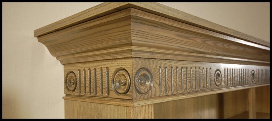 Premier showcase of a handcrafted freestanding bookcase featuring elegant rosettes, fluted moldings, and custom crown molding.