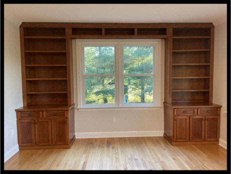 Custom cherry cabinetry wrapping twin windows; Mission style doors with staggered offset drawers and overhead bookcase tower.